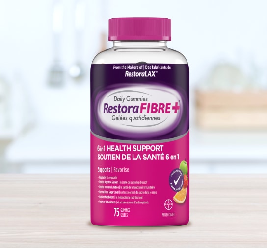 A clear bottle of RestoraFIBRE+® Daily Gummies with a pink cap and a vibrant pink and purple label, detailing 